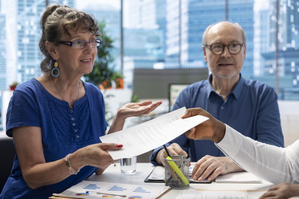 Un conseiller présente des documents de préparation de la retraite à des personnes âgées
